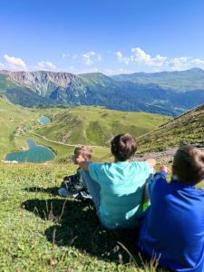 three people sitting on a hill looking at a valley at Mountain View in Goderdzi