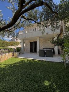 a house with a patio with a table in the yard at Apartments Jela in Splitska