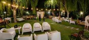 a garden with white chairs and tables and lights at El Indio - Casa de Campo con Piscina y Parrilla in Villa del Salvador