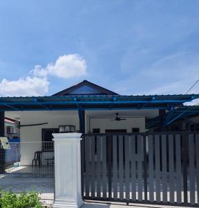a white house with a gate and a fence at Homestay Ayong in Parit Raja