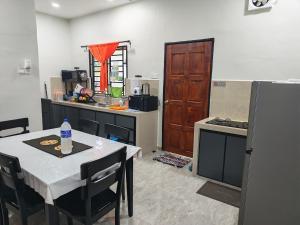 a kitchen with a table and a stove and a refrigerator at Homestay Ayong in Parit Raja