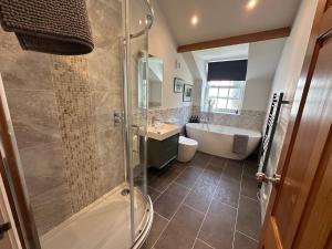 a bathroom with a shower and a tub and a sink at The Little Vicarage in Highbridge +14 photos