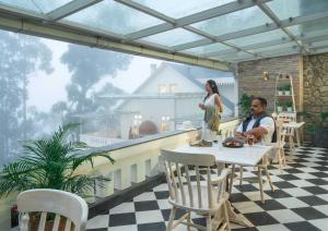 a man and a woman sitting at a table on a patio at 1924 Clock House Munnar in Munnar