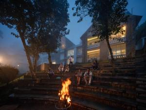 a group of people sitting around a fire in front of a building at 1924 Clock House Munnar in Munnar