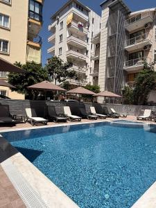 a swimming pool with chairs and umbrellas next to some buildings at Livane Beach Hotel in Alanya