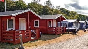 a red cabin with a fence and tents at Morsø Camping in Nykøbing Mors
