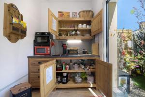 a kitchen with wooden shelves and a microwave at Comme à la maison in Ducey