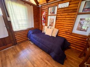 a bedroom with a blue bed in a room with wooden walls at La Posada del Hobbit in Villa Ventana