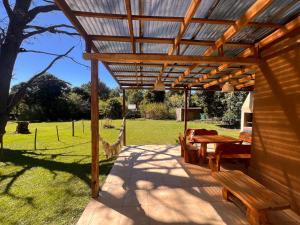 a patio with a wooden pergola and tables and chairs at La Posada del Hobbit in Villa Ventana