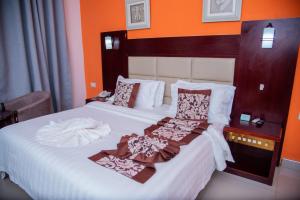 a bedroom with a bed with white sheets and orange walls at Mika Convention Center in Lusaka