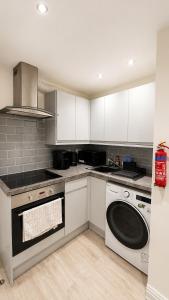 a kitchen with white cabinets and a dishwasher at Cosy Flat on the Top Floor in Ramsbottom in Ramsbottom