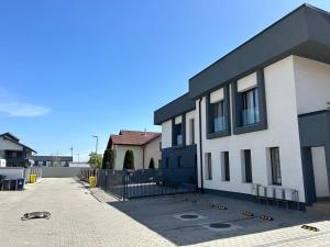 a white and black building with a fence next to it at New House Sibiu in Sibiu