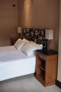 a bedroom with a bed and a nightstand with two lamps at Casa Entonada - Hotel Boutique in Chacras de Coria