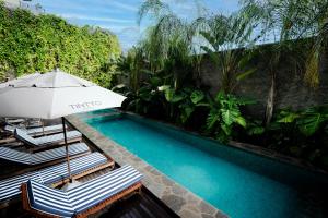 a swimming pool with two chairs and an umbrella at Tintto Hotel in Fortaleza