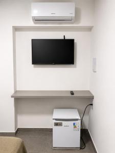 a room with a tv on a white wall at Manaira Suite 02 in João Pessoa