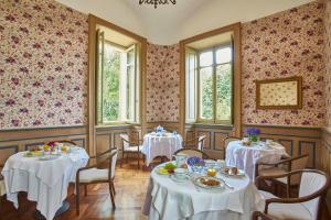 a dining room with two tables with white tablecloths at Sina Villa Matilde in Romano Canavese