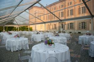 a marquee with white tables and chairs with flowers at Sina Villa Matilde in Romano Canavese +90 photos