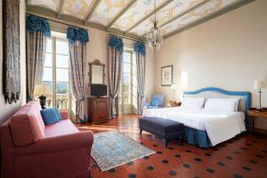 a bedroom with a bed and a couch and a tv at Sina Villa Matilde in Romano Canavese