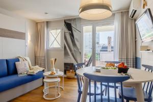 a living room with a blue couch and a table and chairs at Résidence Pierre & Vacances La Baie des Sables in Les Sables-d'Olonne