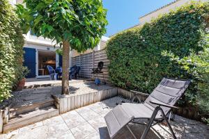 a chair sitting on a patio next to a tree at Maison La Parée Plage in Bretignolles-sur-Mer