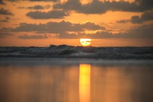 a sunset over the ocean with a wave at Vila hangloose pôr do sol in Acaraú