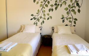 two beds in a room with a tree mural on the wall at Herdade do Burrazeiro Turismo Rural no Alentejo in Borba +66 photos