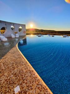 a large swimming pool with a sunset in the background at Herdade do Burrazeiro Turismo Rural no Alentejo in Borba