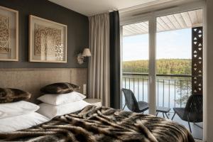 a bedroom with a bed with a view of a balcony at Aries Lago Park Hotel & SPA, Mazury in Olsztynek