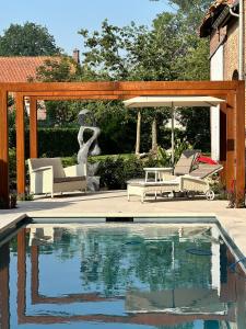 a swimming pool with two chairs and a gazebo at B&B De Rentmeesterhoeve in Reningelst