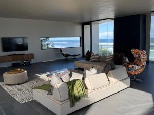 a living room with white furniture and a television at The Ocean View Guest House in Wilderness