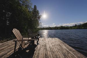 two chairs sitting on a dock next to a lake at Obuoliu sala Moletu Vila in Gaylyunay