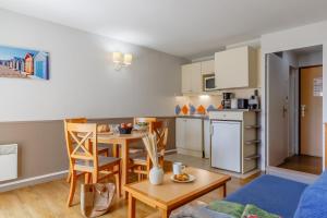 a living room with a table and a kitchen at Résidence Pierre & Vacances La Baie des Sables in Les Sables-d'Olonne +34 photos