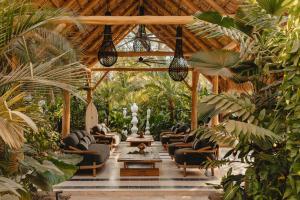 a living room with a bunch of chairs and plants at Domo Nosara Boutique Hotel in Nosara