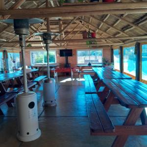 a large wooden picnic table in a building with windows at Complejo de Cabañas Tierra Nuestra in Mina Clavero
