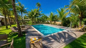 a swimming pool with chairs and palm trees at Resort Costa Dos Coqueiros in Imbassai