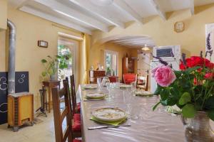 a dining room with a table with a vase of flowers at Le Duzon avec Piscine in Saint-Sylvestre