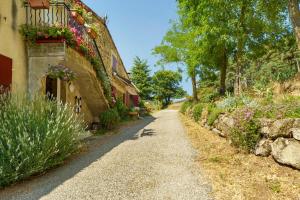 a dirt road next to a building with flowers on it at Le Duzon avec Piscine in Saint-Sylvestre