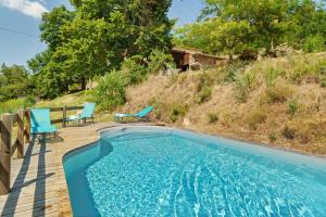 a swimming pool with two blue chairs on a wooden deck at Le Duzon avec Piscine in Saint-Sylvestre