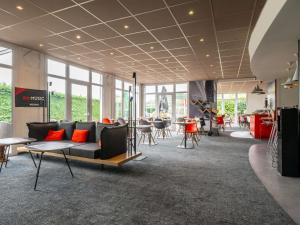 a lobby with a couch and tables and chairs at ibis Issoire in Issoire