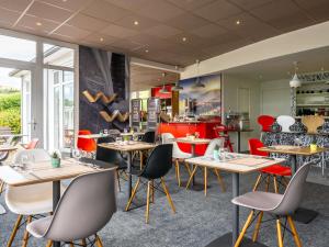 a restaurant with tables and chairs and a kitchen at ibis Issoire in Issoire