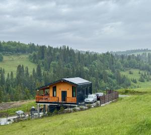 a house on a hill with cars parked in a field at Гимба in Podobovets