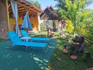 a yard with two blue chairs and an umbrella at Casa de vacanta 1001 De Nopti in Corbşori