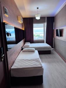 a hotel room with three beds and a window at Temiz Hotel in Alanya