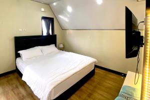 a bedroom with a white bed and a television at villa cabin vianda in Kejajar