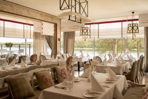 a restaurant with white tables and chairs and windows at Aries Lago Park Hotel & SPA, Mazury in Olsztynek