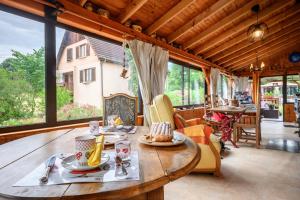 a dining room with a wooden table and large windows at Chambre d'hôte La Châtelaine in Walbach