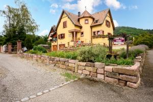 a large yellow house with a stone wall at Chambre d'hôte La Châtelaine in Walbach