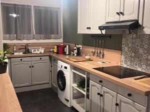 a kitchen with white cabinets and a washer and dryer at Eden-Novia in Orléans