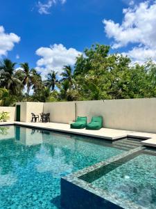 a swimming pool with two green cushions next to a wall at Nilaveli Boutique Hotel in Trincomalee