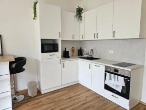 a white kitchen with white cabinets and a stove top oven at Apartmán Meridiem Komárovská in Komárov